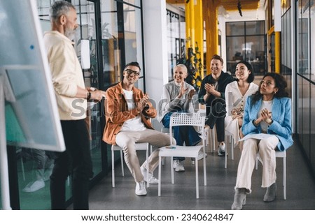 Group of multiethnic colleagues smiling while discussing business strategy for new company development during conference in modern office together looking at each others Royalty-Free Stock Photo #2340624847