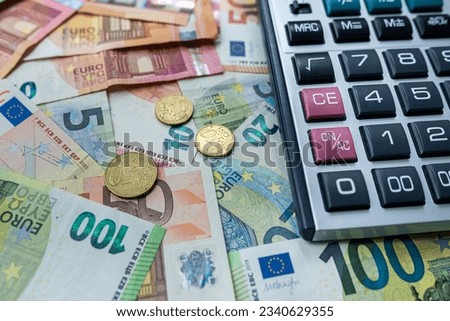 Euro coin and calculator above euro bills. Saving and finance concept. Investment theme Royalty-Free Stock Photo #2340629355