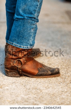 Cowboy standing in bluejeans and typical cowboy boot on hard surface. Royalty-Free Stock Photo #2340642545