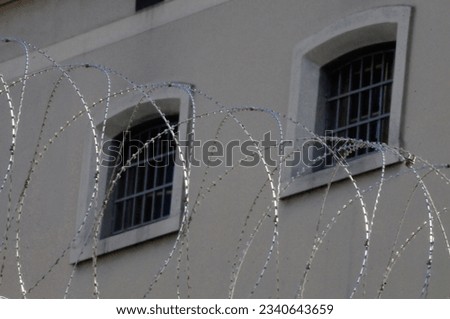 a prison window with bars and razor wire in front of it Royalty-Free Stock Photo #2340643659