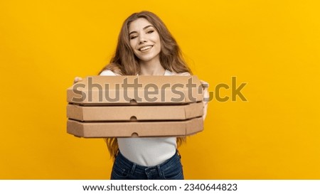 This photo captures the joy of a pizza delivery, with a woman holding a stack of boxes on a bright yellow background