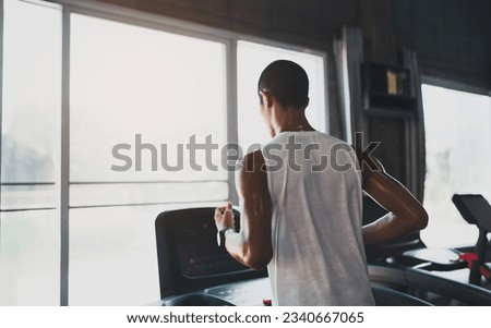 Back side of asian sportman runner running on treadmill in fitness club. Cardio workout. Healthy lifestyle, guy training in gym. Sport running concept. Royalty-Free Stock Photo #2340667065