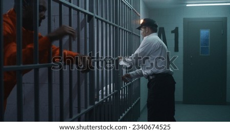 Warden brings new prisoner in jail cell and takes off his handcuffs. African American criminals serve imprisonment term in correctional facility or detention center. Guilty murderers in prison cells. Royalty-Free Stock Photo #2340674525