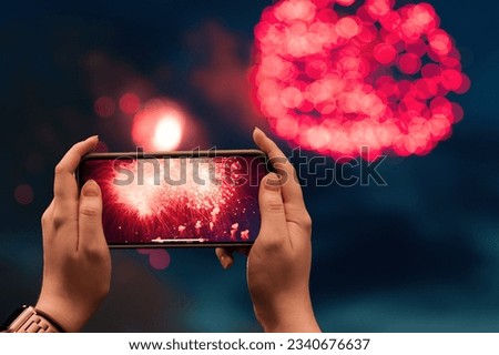 Woman hands with mobile phone to take a photo of fireworks Royalty-Free Stock Photo #2340676637