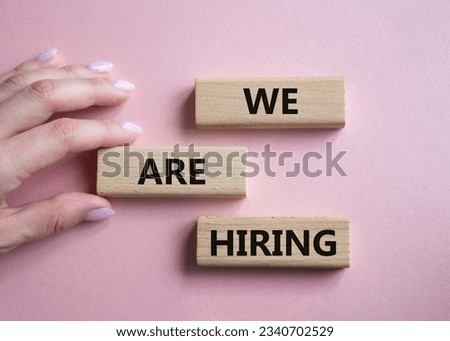 We are Hiring symbol. Concept words We are Hiring on wooden blocks. Businessman hand. Beautiful pink background. Business and We are Hiring concept. Copy space.