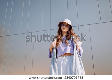 Young hip hop girl in oversize outfit wearing dancing into music minimalistic urban background.  Royalty-Free Stock Photo #2340709785