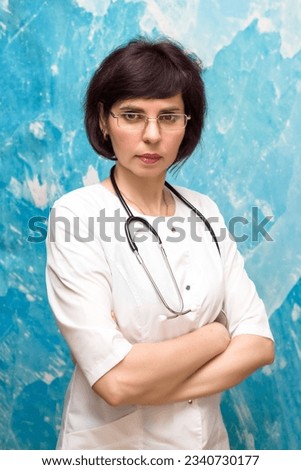 Portrait female doctor 40-44 years old near a blue wall. Royalty-Free Stock Photo #2340730177