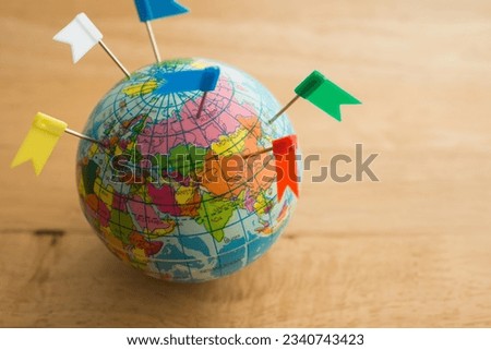 Color flag pins marks on earth globe with wooden table background copy space. Travel holiday vacation destination, business trip, abroad education, company branch concept.