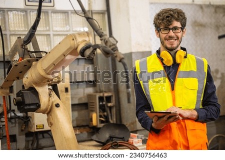 portrait happy young caucasian male worker robot arm machine operator in metal factory Royalty-Free Stock Photo #2340756463