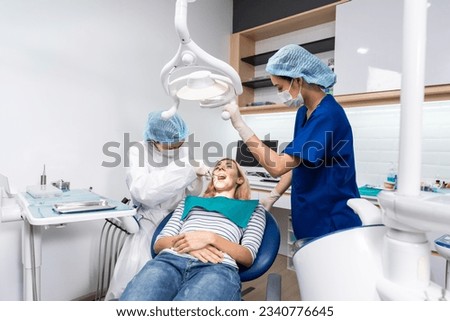 Female dentist examine tooth to Caucasian girl at dental health clinic. Attractive woman patient lying on dental chair get dental treatment from doctor during procedure appointment service in hospital Royalty-Free Stock Photo #2340776645