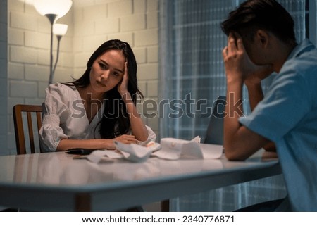 Asian young depressed couple having argument while checking money debt. Attractive new marriage man and woman looking frustrated to paperwork and bill, feel worried about financial problem in house. Royalty-Free Stock Photo #2340776871