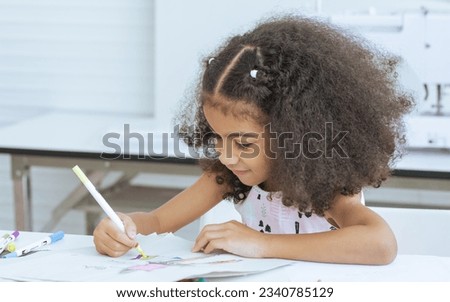 Cute African little girl drawing or sketching clothing design on paper at tailor room, cozy home as her career dream, smiling with happiness and fun. Leisure, Lifestyle, Education, Kid Concept
