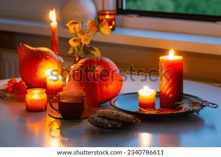 autumn still life with pumpkins, burning candles and cup of tea