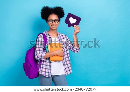 Photo of positive nice girl dressed checkered shirt backpack on shoulder holding book like icon isolated on blue color background
