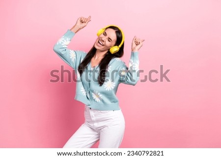 Photo of adorable woman with long hairstyle dressed blue cardigan dancing hold hands up in headphones isolated on pink color background