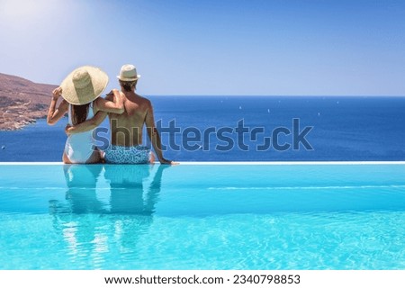 A couple hugging at the edge of an infinity pool and enjoying the view to the blue, mediterranean sea during summer vacation time Royalty-Free Stock Photo #2340798853