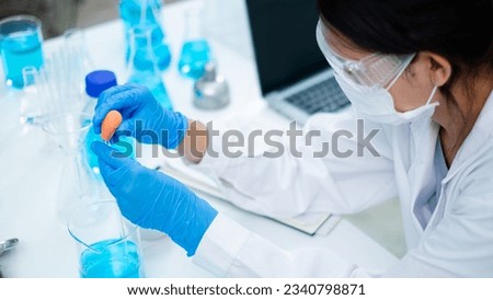 Asian woman scientist is dropping blue liquid substance in science test tube in laboratory. Concept of science, biochemistry, chemical, diagnosis, biotechnology. Substance study analyzing experiment