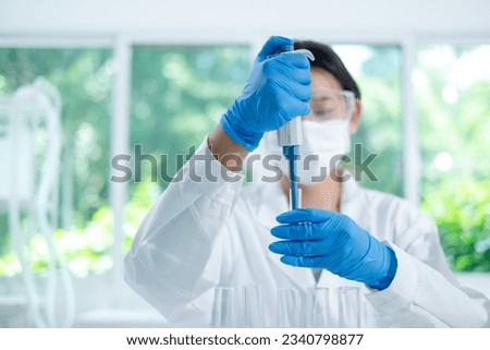 Asian woman scientist is dropping blue liquid substance in science test tube in laboratory. Concept of science, biochemistry, chemical, diagnosis, biotechnology. Substance study analyzing experiment