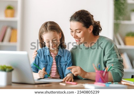 Happy child and adult are sitting at desk. Girl doing homework or online education. Royalty-Free Stock Photo #2340805239