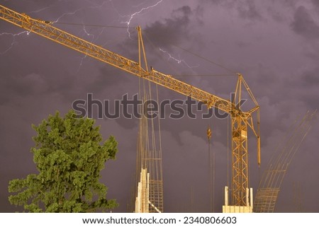 Timelapse photography of construction crane with thunder in stormy sky in background