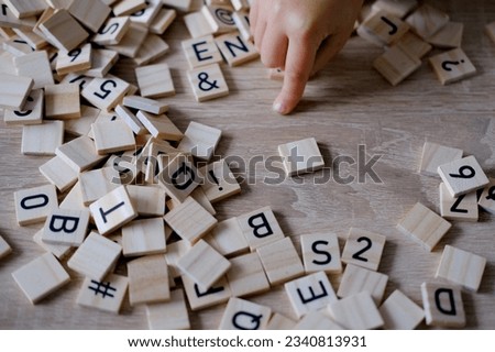 hands close-up, small child 3 years old plays wooden alphabet blocks, makes up words from letters, dyslexia awareness, learning difficulties, human brain development, happy childhood, selective focus Royalty-Free Stock Photo #2340813931