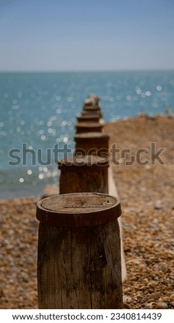 The wooden and metal groynes disappearing into distance on the pebble beach at Brighton, first one sharp and rest in bokeh with turquoise sea and blue sky Royalty-Free Stock Photo #2340814439