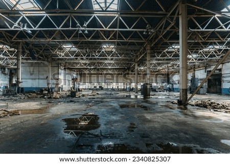 Abandoned factory. Large empty ruined industrial hall with broken remnants of equipment. Royalty-Free Stock Photo #2340825307