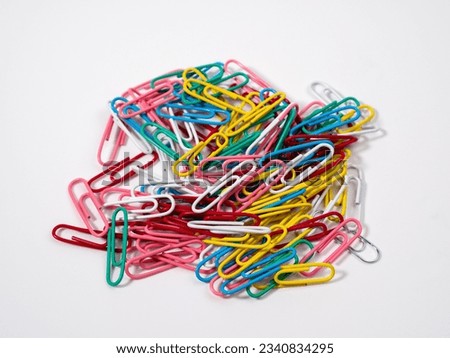 Multicolored paper clips on a white background. Colored paper clips close up.
