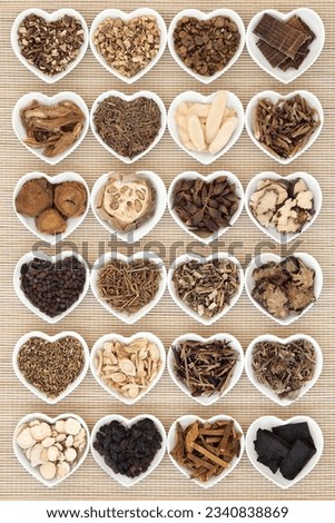Large chinese herbal medicine selection in heart shaped porcelain bowls over bamboo background.