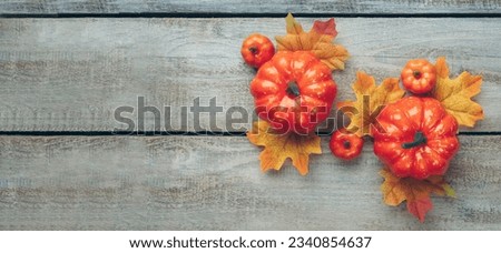 Thanksgiving and Autumn decoration concept made from autumn leaves and pumpkin on wooden light background. Flat lay, top view with copy space.