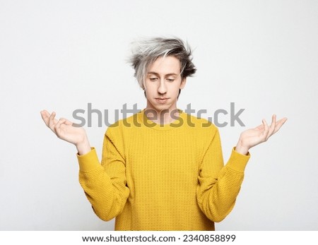 young attractive man wearing yellow sweater astonished and amazed in shock and surprise face expression isolated on white background