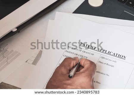 Man filling out Patent Application form for invention. Close-up view, selective focus.  Royalty-Free Stock Photo #2340895783