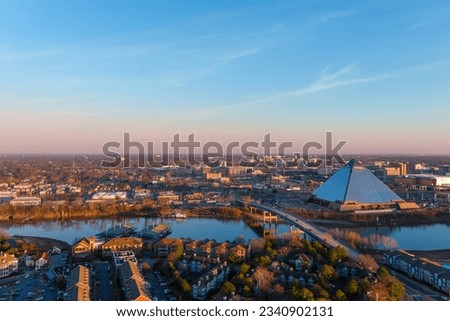a stunning aerial shot of the the skyscrapers and office buildings in the cityscape along Wolf Creek Harbor with a glass pyramid and powerful clouds at sunset at Greenbelt Park on Mud Island
