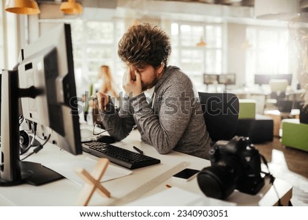 Young male photographer editing photos on his computer while working from the office