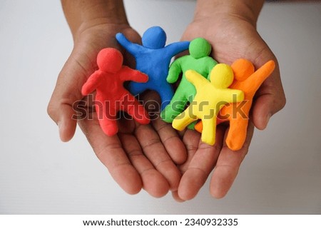 Close up hands holds colorful plasticine people. Human figures from plasticine sculpture.  Concept, friendships, partnerships and relationships between people. Sculting enhance imagination.       