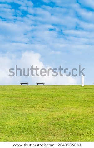 Garden bench with Green meadows with blue sky and clouds background, Landscape view of green grass on slope Scenic panoramic view on a beautiful sunny day,japanese picture concept.