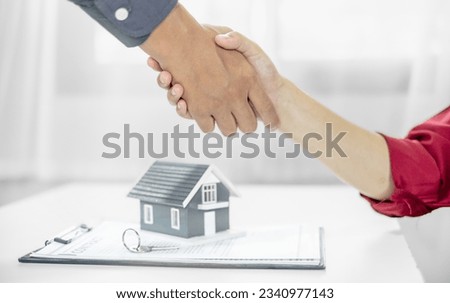 Businessmen and brokers real estate agents shake hands after completing negotiations to buy house insurance and sign contracts. Home insurance concept.