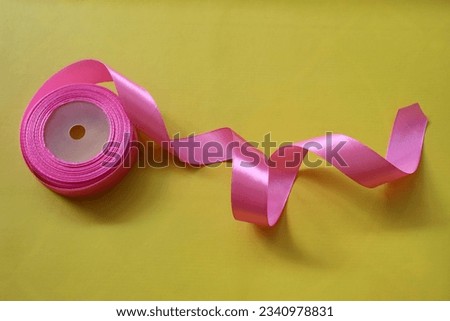 Roll of pink ribbon. Can be used for gift wrapping or for symbolizes breast cancer awareness. October Breast Cancer Awareness month. Isolated on yellow background.