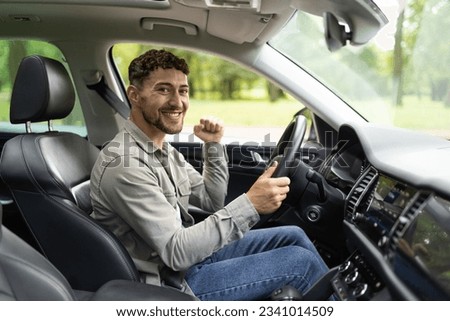 Young hispanic man smiling happy doing ok sign driving car.