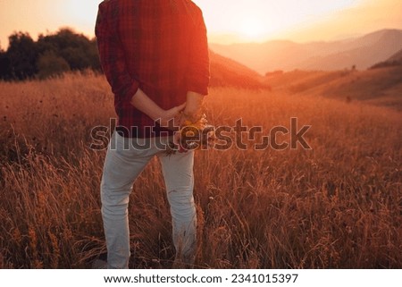 Man holding field flowers in nature.