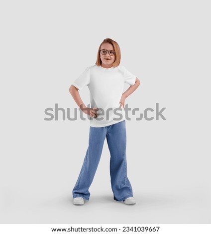 Mockup of white t-shirt on smiling girl in jeans with hands on waist, blank shirt, isolated on background, front view. Template of fashionable kids clothes for design, product photography for commerce
