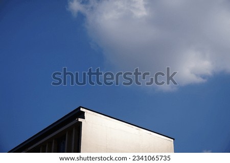 the building turned white because it was hit by light On a day when the sky is dark blue There was a big white cloud floating around, waiting for the letters to fill this picture with more meaning.