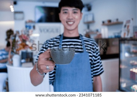The barista serves customers coffee mugs in the cafe, handing them coffee mugs to the front of the cafe.
