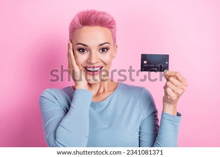 Photo of impressed woman with short haircut dressed blue sweatshirt hand on cheek hold credit card isolated on pink color background