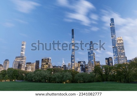 Manhattan skyscrapers and Central Park meadow at sunset Royalty-Free Stock Photo #2341082777