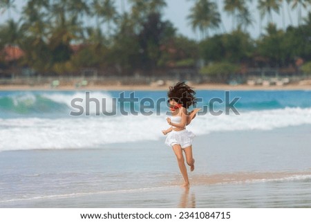 A slender girl in white clothes runs along the beach against the background of the sea. Healthy woman on the beach. A sports girl runs along the embankment of the sea. High-quality photo
