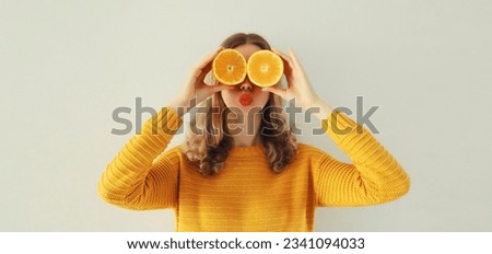 Summer, nutrition, diet and vegetarian concept. Happy healthy cheerful young woman covering her eyes with slices of orange fruits and looking for something on white background