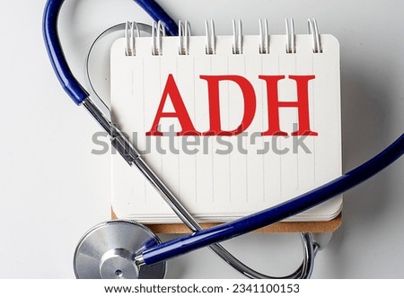 ADH word on a notebook with medical equipment on background
