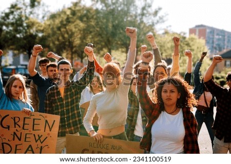 young crowd in protest demonstration - group of activists in march with raised fist Royalty-Free Stock Photo #2341100519
