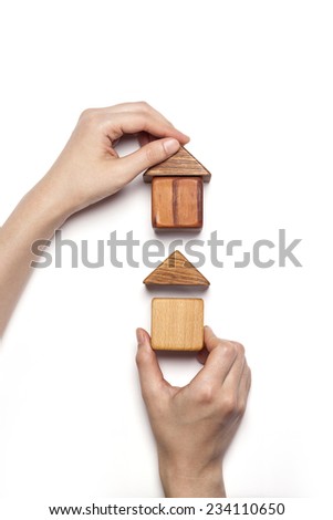 A female hand hold(pick up) the wood block among the wood blocks like two house(real estate) isolated white, top view at the studio.